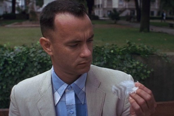 L'attore Tom Hanks, nel ruolo di Forrest Gump, osserva una piuma d'uccello.